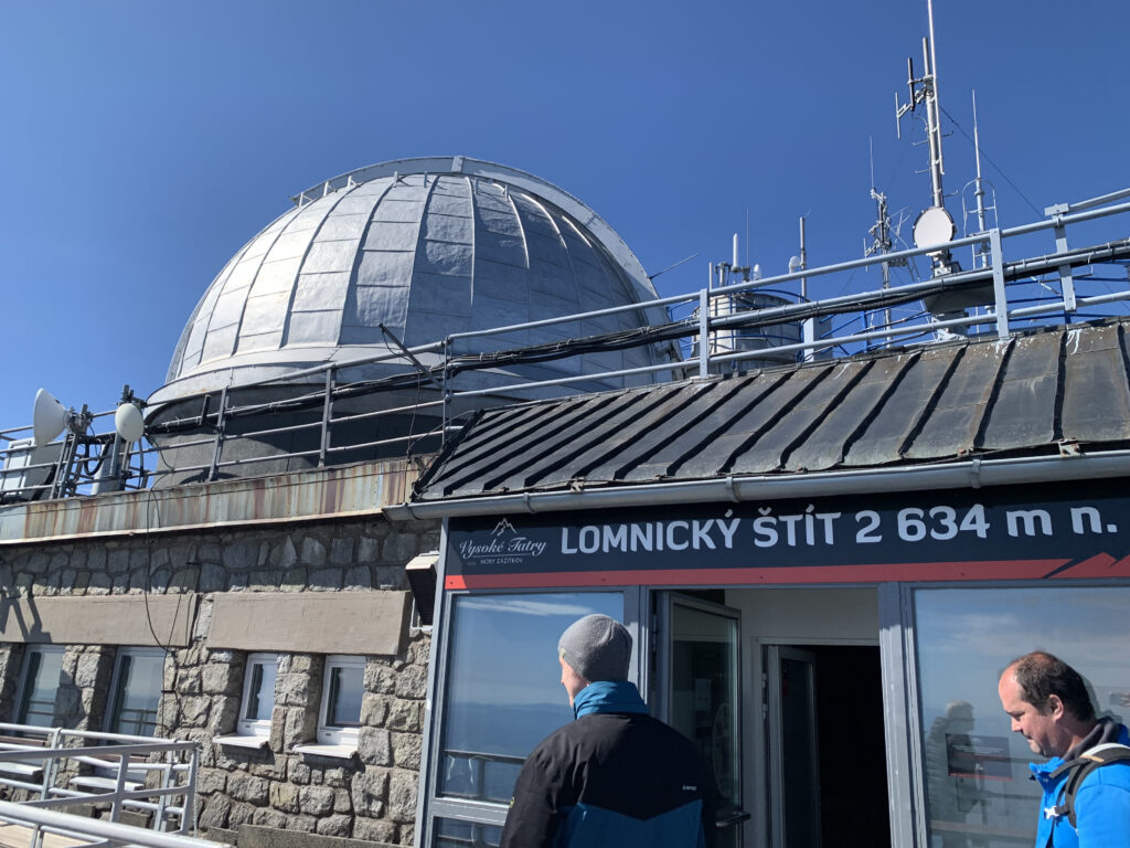 Entrance to the observatory at Lomnický štít, 2,634 meters above sea level, with a domed roof and antennas under clear blue sky