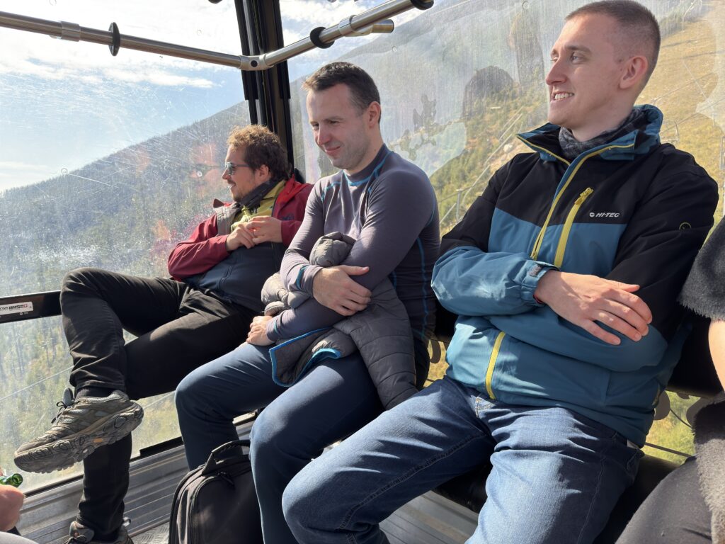 Group of colleagues sitting in a cable car with mountain scenery visible through the window