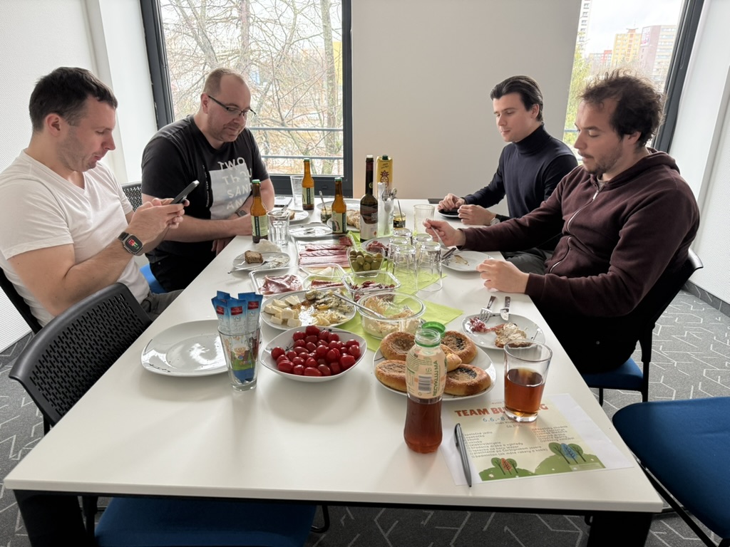 Team members gathered around a table enjoying an Easter-themed office feast with festive food, drinks, and a relaxed atmosphere.
